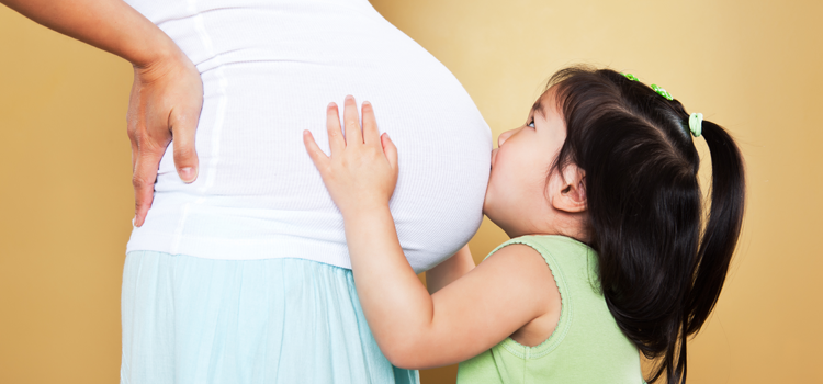 toddler kissing mom&#039;s pregnant belly