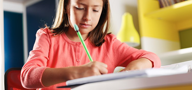 girl sits at desk doing homework