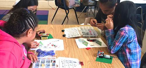 Girls building LEGO projects together