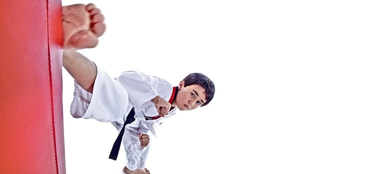 boy martial arts kicking a pad