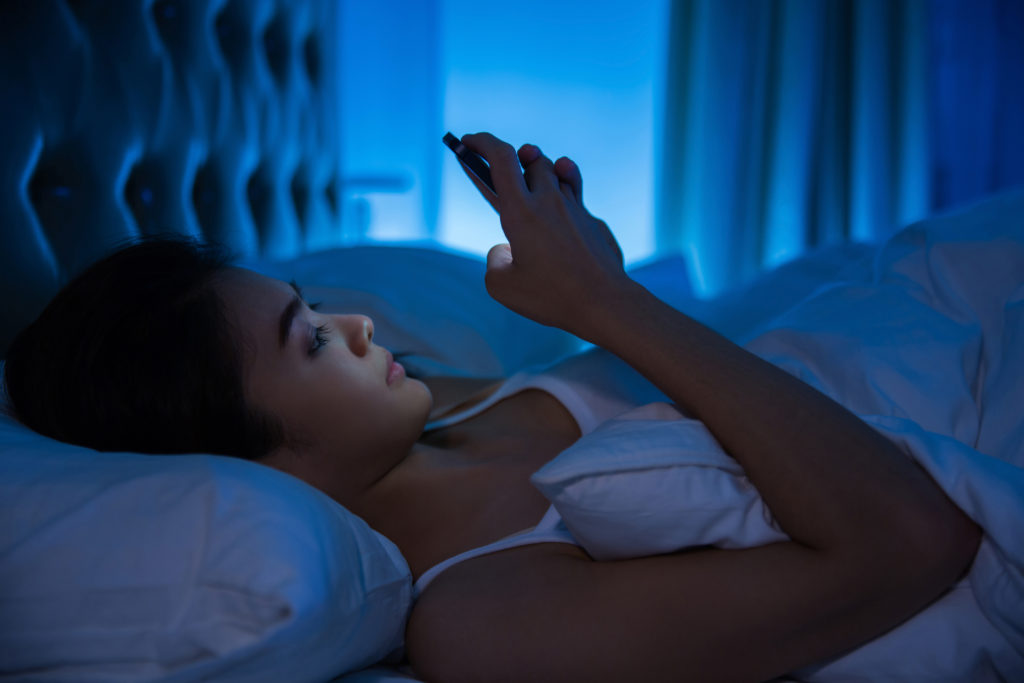 Woman using a smart phone on the bed 